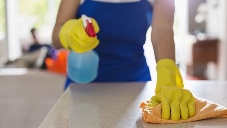 A close-up of a professional house cleaner wiping a surface.